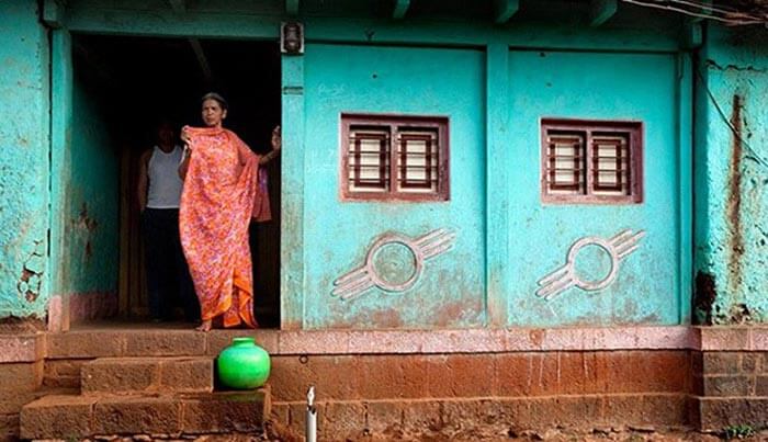 A woman looks outside her doorless house at Shani Shignapur