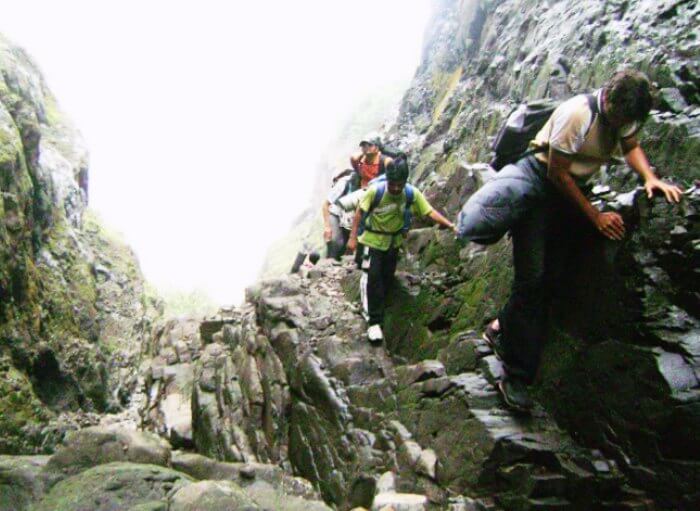 Trekkers climbing the rocks of Harishchandragad Fort