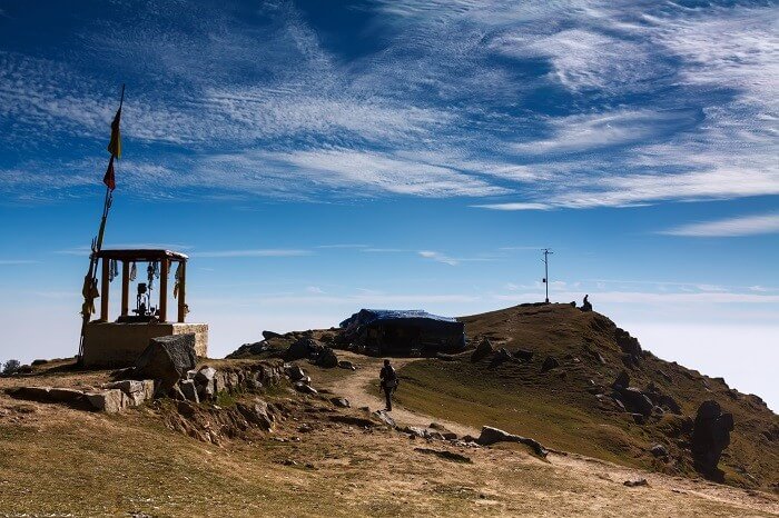 A man passes by the hilltop flag and temple at Triund