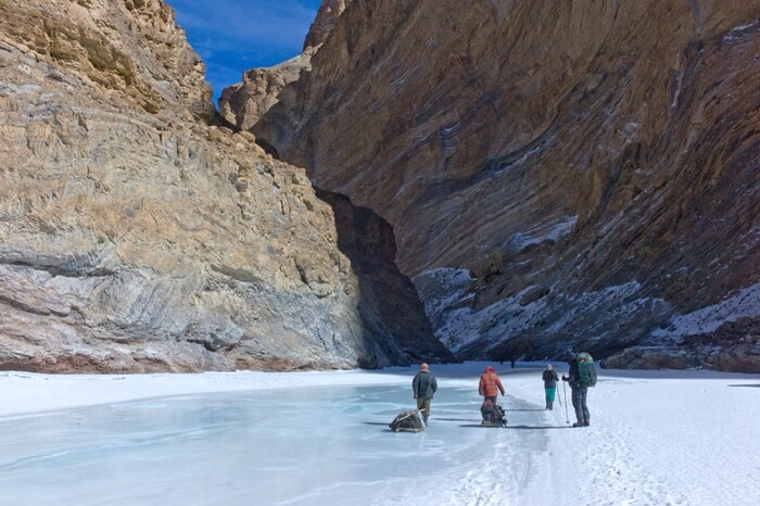 Travelers walking the frozen lake while walking the Chadar trek