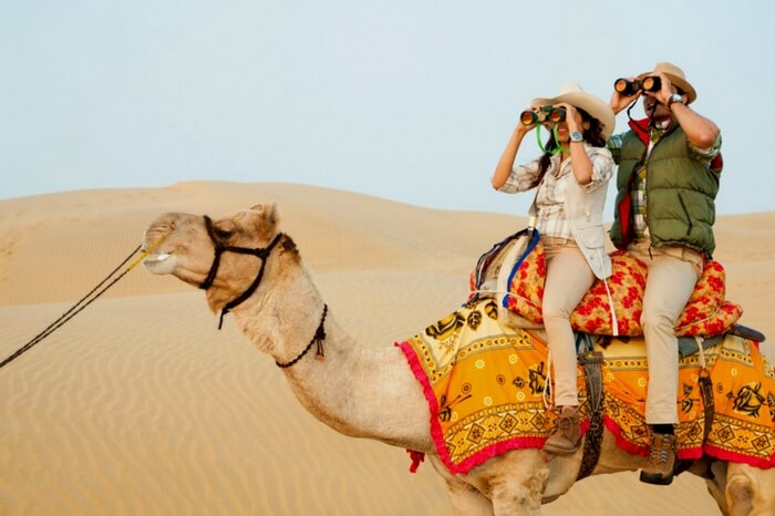 People exploring the vast dunes of desert while enjoying camel safari in Jaisalmer